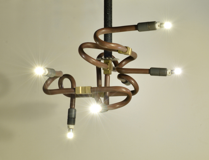 Other than light the primary components of this hanging work are iron loops that were a flea market find which the seller had no idea what they were used for. When I see something at the flea market I just respond to it as an object of interest. The gestation of the idea for this hanging piece occurred while making random arrangements of the loops for fun.